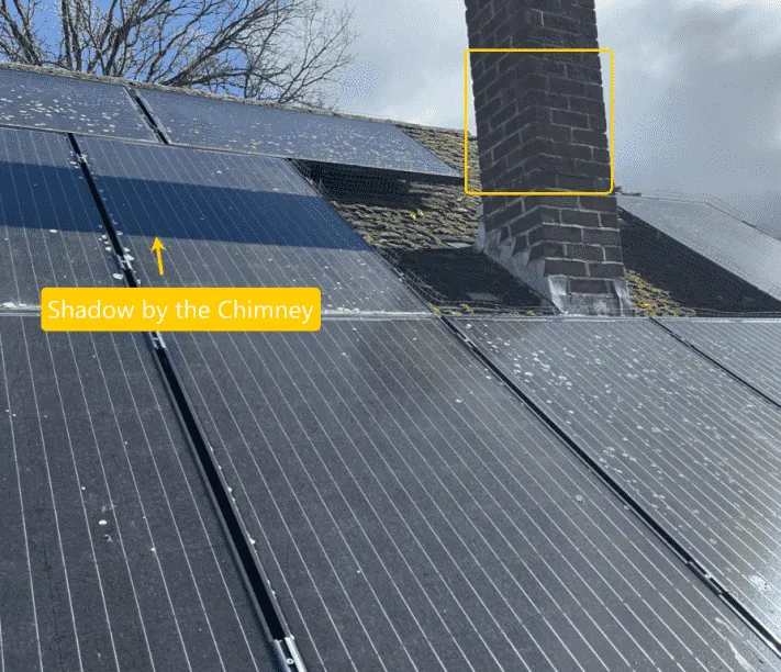 The shadow of the chimney casts a shadow on the solar panel.