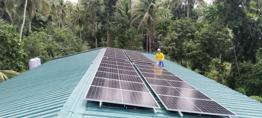 Workers install solar panels on the roof